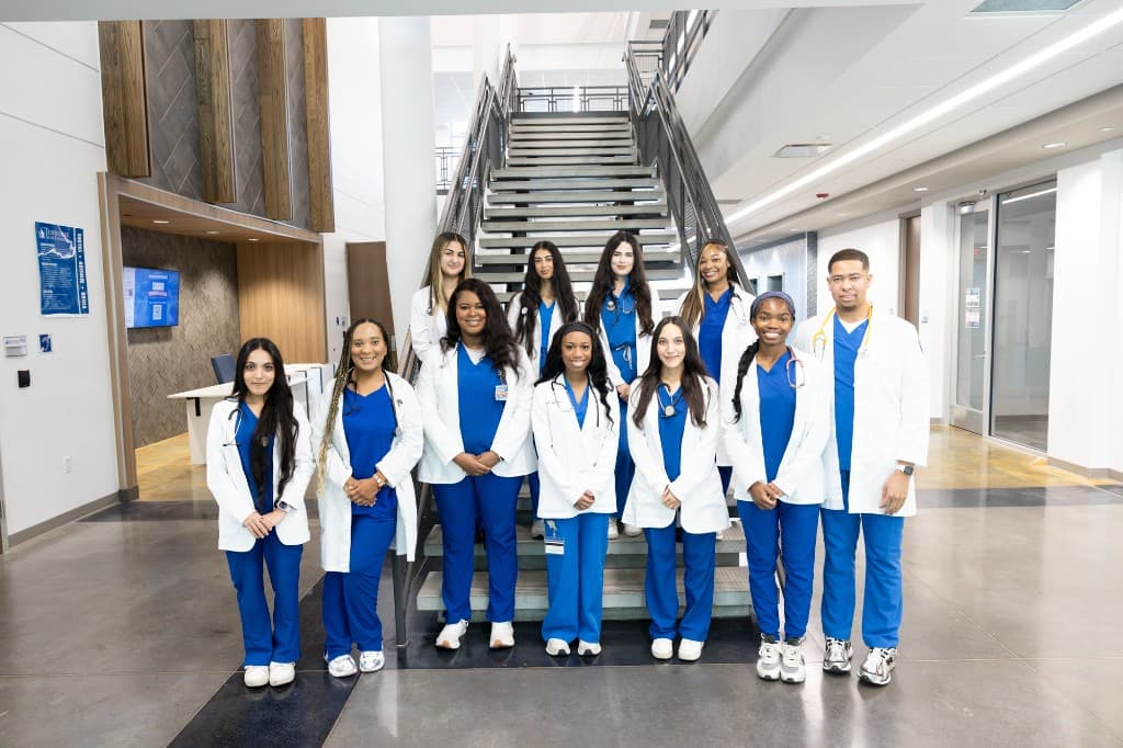 Tennessee State University respiratory therapy students and faculty standing on a stairway in blue scrubs and white coats